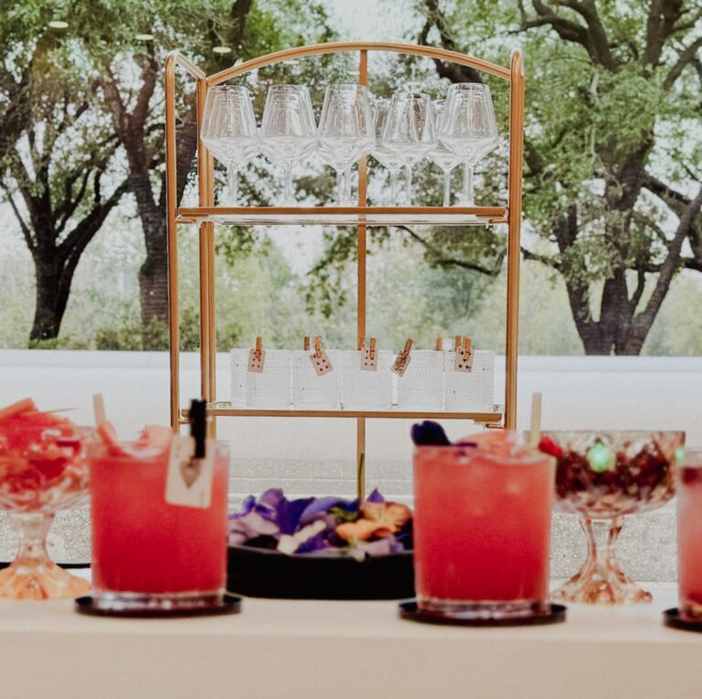 Luxury mobile bar setup in Houston for a Casino Royale corporate event featuring signature cocktails, white bar with pillars, gold back bar, and elevated presentation.