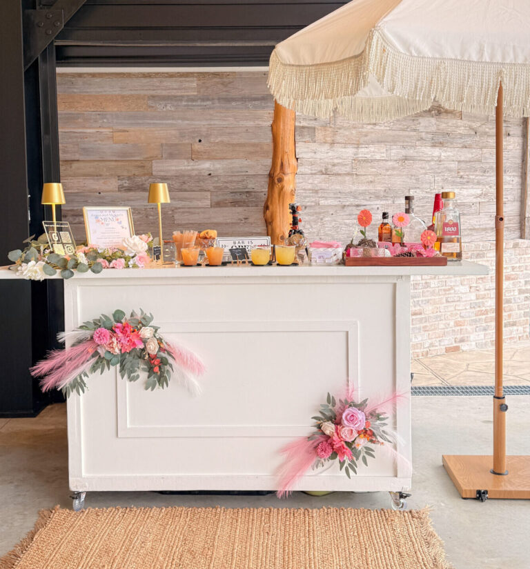 Houston mobile bar setup with white bar, umbrella, floral decor, and custom cocktails by I’ll Drink To That!