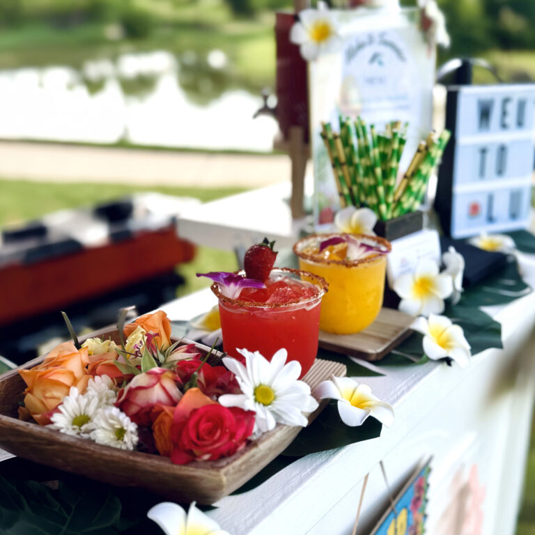Colorful signature cocktails with tropical flowers at a luau-themed community event in Houston