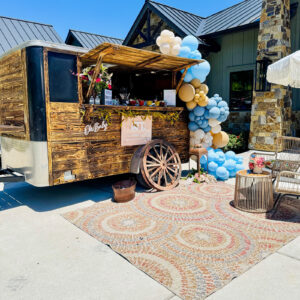 Rustic trailer bar decorated with blue white and gold balloons for a Houston baby shower