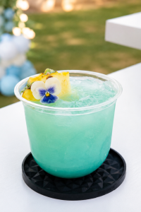 Blue Hawaiian Mocktail with Flower Garnish | I’ll Drink To That! Blue Hawaiian mocktail with pineapple garnish and edible flower on a white bar counter