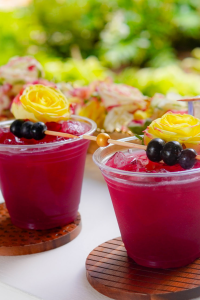A sparkling mocktail or Cocktail called Berry Bright Spritzer, made with fresh blueberries, mint, lemon, and soda water, served over ice in a tall glass with a blueberry and mint garnish.