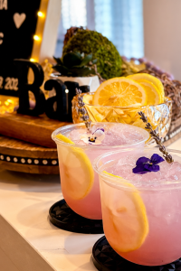 Lavender Lemonade Mocktail | I’ll Drink To That! Lavender lemonade mocktail with lemon slices, edible flowers, and lavender garnish at a mobile bar event